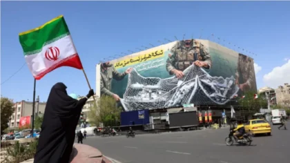 selat hormuz seorang wanita memegang bendera iran sambil berdiri di dekat papan reklame dengan kalimat bertuliskan selat hormuz tetap ditutup di lapangan enqelab di teheran ahad 54 afp id4j